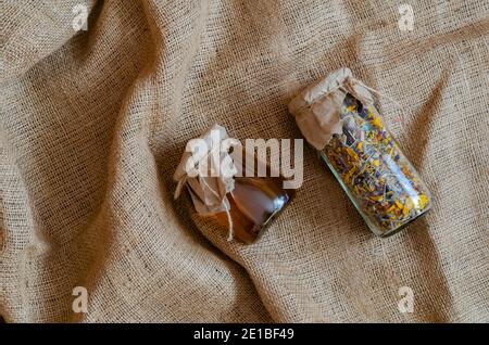 Herbes médicinales et médecine alternative concept.Herbal herbes séchées médicinales et miel d'abeille. Thé de fleur séché et miel liquide cru dans des pots en verre sur toile de jute. Banque D'Images