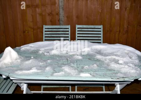 gros plan sur l'image en noir et blanc de la neige recouverte table de jardin rustique avec chaises vides à l'extérieur en hiver Banque D'Images