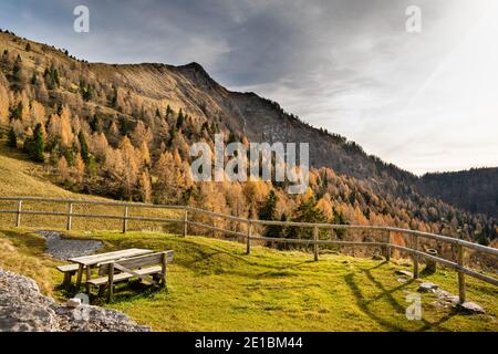 Panorama avec ciel nuageux, montagnes et pentes bordées d'arbres. Dans la table de premier plan et le banc en bois. Cesiomaggiore, Belluno, Italie Banque D'Images