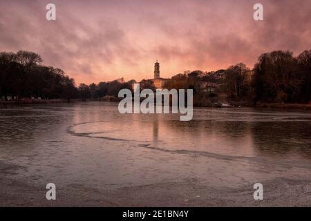 Lever du soleil tôt le matin lumière au-dessus d'un lac gelé à Highfields University Park, Nottingham Notinghamshire Angleterre Royaume-Uni Banque D'Images