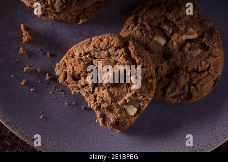 Triple biscuits aux pépites de chocolat avec des morceaux de lait blanc et photo de chocolat noir avec éclairage créatif sombre Banque D'Images