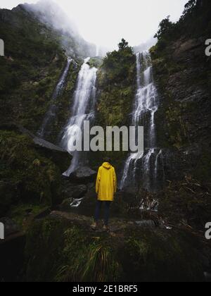 Jeune homme en blouson jaune devant El Chorro De Giron cascade cascade cataracte près de Cuenca Azuay Equateur in Amérique du Sud Banque D'Images