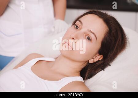 Gros plan d'une patiente triste à l'hôpital. Une jeune femme malheureuse, couchée dans son lit à la clinique, attend une intervention chirurgicale Banque D'Images