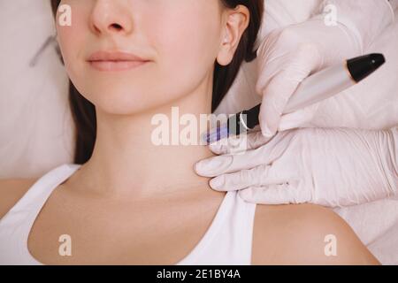 Prise de vue courte d'une femme méconnaissable recevant des microinjections dans sa peau de cou. Cosmétologue utilisant dermapen sur le client féminin Banque D'Images