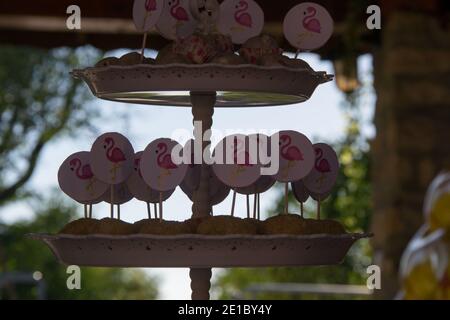 Gros plan de petits gâteaux faits maison avec des bâtons de flamants roses sur un présentoir à gâteaux, concept de fête, bonbons pour la fête d'anniversaire Banque D'Images