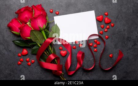 Carte de voeux pour la Saint-Valentin avec fleurs roses rouges et bonbons en forme de coeur. Plan d'accueil avec vue de dessus et espace pour vos salutations Banque D'Images