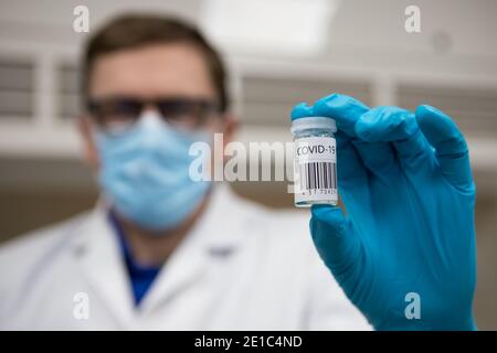 Dose de vaccination du coronavirus prête pour l'immunisation. Médecin avec des mains gantées tenant un flacon en verre de vaccin Covid-19 Banque D'Images