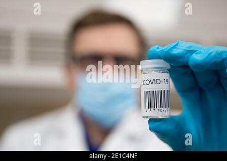 Dose de vaccination du coronavirus prête pour l'immunisation. Médecin avec des mains gantées tenant un flacon en verre de vaccin Covid-19 Banque D'Images