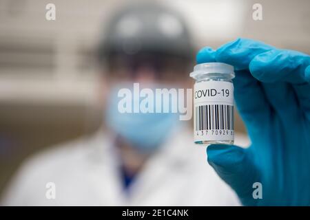 Dose de vaccination du coronavirus prête pour l'immunisation. Médecin avec des mains gantées tenant un flacon en verre de vaccin Covid-19 Banque D'Images
