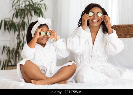 Joyeux maman noire et fille dans des peignoirs de bain ayant le jour de beauté À la maison Banque D'Images