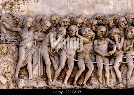 Un ange vengeant conduit les damnés en enfer dans les années 1300 dernier jugement bas-relief en marbre sur la façade ouest de la cathédrale d'Orvieto, Ombrie, Italie. Cette scène sculptée est attribuée à Lorenzo Maitani (c. 1275 - 1330), qui a conçu la façade gothique tardive de la cathédrale. Maitani aurait eu une contribution directe en tant que sculpteur sur deux panneaux couvrant deux des quatre pilastres inférieurs de la façade : un panneau de Maitani représente des scènes du jugement dernier, y compris la scène dans cette image. Banque D'Images