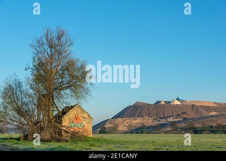 Wolmirstedt, Allemagne. 19 décembre 2020. Une maison en ruines se trouve dans un champ à côté d'une hauteur. Derrière elle, on peut voir la pile de résidus de l'usine de potasse de Zielitz. La société K S élargira la pile de résidus de 200 hectares au cours des prochaines années. Cette autorisation a été accordée par l'Office d'État pour la géologie et l'exploitation minière (LAGB). Cela permettra d'assurer la production d'engrais et de sel à Zielitz jusqu'en 2054. Le tas de résidus est également appelé Kilimandjaro. Credit: Stephan Schulz/dpa-Zentralbild/ZB/dpa/Alay Live News Banque D'Images