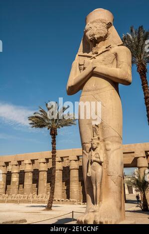 Louxor. Voici la statue de Ramasses II, le Grand avec sa fille Bentanta à ses pieds à l'entrée du temple de Karnak, âgé de 4000 ans, le plus grand complexe de temples du monde, Situé sur le Nil dans la ville de Louxor, autrefois connue dans le monde antique sous le nom de Thèbes. Les terrains du temple ont également été utilisés comme un ensemble de films pour le film James Bond The Spy qui aimait moi. Banque D'Images