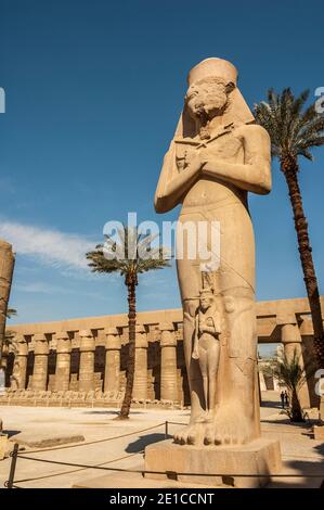 Louxor. Voici la statue de Ramasses II, le Grand avec sa fille Bentanta à ses pieds à l'entrée du temple de Karnak, âgé de 4000 ans, le plus grand complexe de temples du monde, Situé sur le Nil dans la ville de Louxor, autrefois connue dans le monde antique sous le nom de Thèbes. Les terrains du temple ont également été utilisés comme un ensemble de films pour le film James Bond The Spy qui aimait moi. Banque D'Images