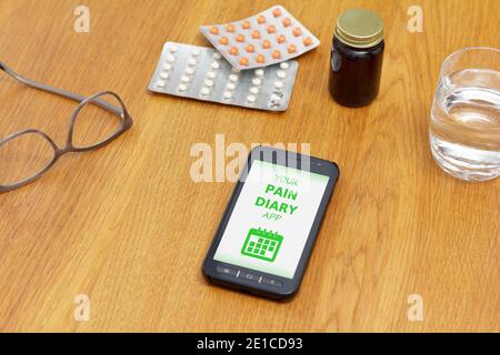 Concept de gestion de la douleur : application de journal de la douleur sur mobile, cellulaire ou smartphone avec verre d'eau, lunettes et médecine. Banque D'Images
