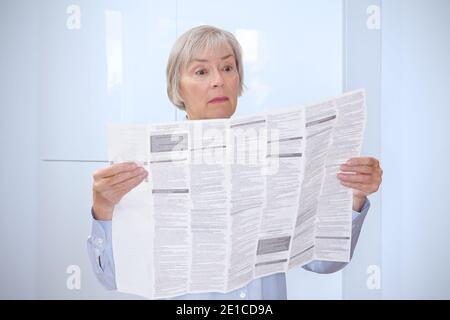 Une femme âgée avec un énorme feuillet d'information patient pour son médicament prescrit. Banque D'Images