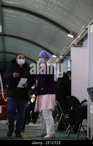 (210106) -- BEIJING, le 6 janvier 2021 (Xinhua) -- UN professionnel de la santé guide les personnes qui viennent pour la vaccination COVID-19 dans un site de vaccination temporaire dans le district de Haidian de Beijing, capitale de la Chine, le 6 janvier 2021. (Xinhua/lu Ye) Banque D'Images