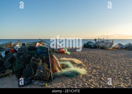 Amaraco da Pera, Portugal - 30 décembre 2020 : coucher de soleil à Praia do Pescadores, sur la côte de l'Algarve, au Portugal, avec bateau de pêche et filets Banque D'Images