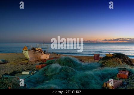 Amaraco da Pera, Portugal - 30 décembre 2020 : coucher de soleil à Praia do Pescadores, sur la côte de l'Algarve, au Portugal, avec bateau de pêche et filets Banque D'Images