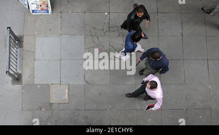 Les piétons de la City de Londres marchant sur une chaussée fissurée avec des mégots de cigarettes qui jontent le sol Banque D'Images