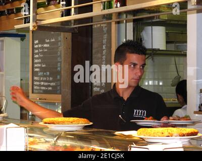 Serveur prêt à emporter les plats à la table au marché de San Miguel à Madrid. Banque D'Images