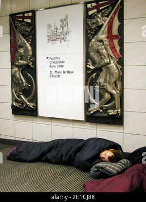 Personne sans-abri dormant dans la ville vagabonds sans-abri dans des sacs de couchage sous l'emblème des armoiries de la City of London, Bank Station London UK Banque D'Images