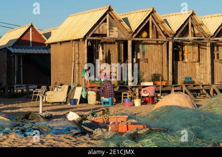 Amaraco da Pera, Portugal - 30 décembre 2020 : fiserman assis à l'extérieur de sa hutte au coucher du soleil et en train de réparer ses filets Banque D'Images