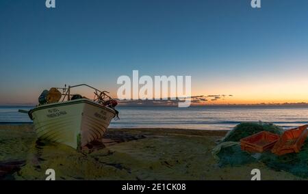 Amaraco da Pera, Portugal - 30 décembre 2020 : coucher de soleil à Praia do Pescadores, sur la côte de l'Algarve, au Portugal, avec bateau de pêche et filets Banque D'Images