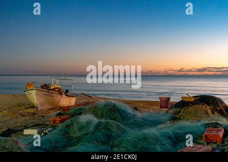 Amaraco da Pera, Portugal - 30 décembre 2020 : coucher de soleil à Praia do Pescadores, sur la côte de l'Algarve, au Portugal, avec bateau de pêche et filets Banque D'Images