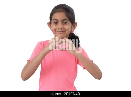 Portrait d'une petite fille indienne mignonne montrant le signe de forme de coeur avec les mains et exprimant l'amour. Banque D'Images