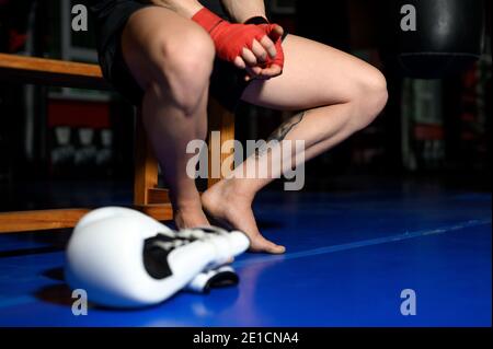 Gros plan des jambes du boxeur reposant sur un banc en salle de gym après l'entraînement. Photo de haute qualité Banque D'Images