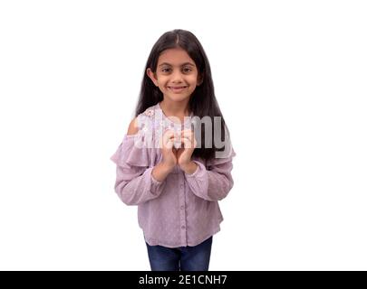Portrait d'une petite fille indienne mignonne avec de longs cheveux montrant le signe de forme de coeur avec les mains et exprimant l'amour. Banque D'Images