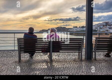 Un couple s'assoit pour profiter du coucher de soleil d'hiver Albufeira Algarve Portugal Banque D'Images