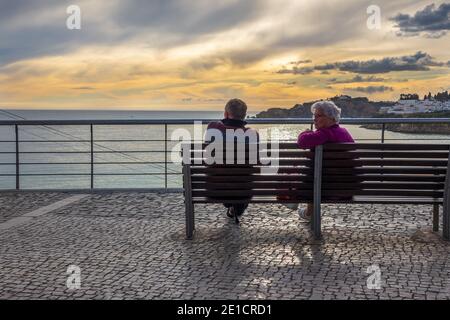 Un couple s'assoit pour profiter du coucher de soleil d'hiver Albufeira Algarve Portugal Banque D'Images