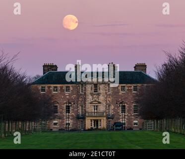 Pleine lune s'élevant dans le ciel rose au-dessus de la maison d'Archerfield House ou manoir, East Lothian, Écosse, Royaume-Uni Banque D'Images