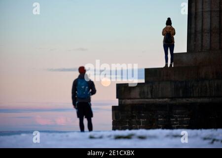 Touristes regardant la lune de Calton Hill, Edinbugh. Pendant le soleil d'hiver avec neige de 2021 Banque D'Images