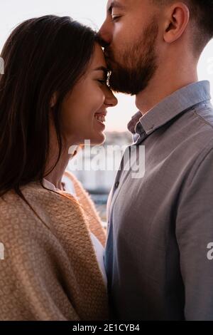 Gros plan portrait, homme et femme souriant les uns aux autres au coucher du soleil avec la ville en arrière-plan. Couple romantique moments intimes Banque D'Images