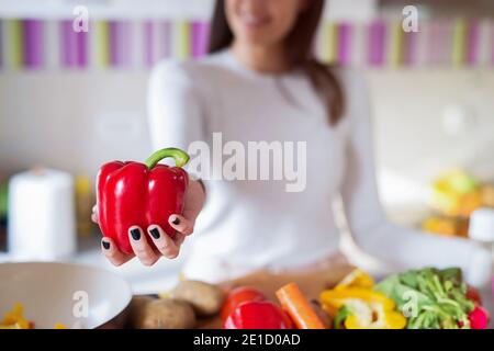 Gros plan d'une fille tenant le paprika rouge dans ses mains. L'accent est mis sur la paprika. Banque D'Images