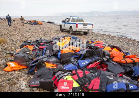 Une voiture de police sur la plage à côté des gilets de sauvetage abandonnés par les migrants syriens fuyant la guerre et s'échappant en Europe, atterrissant sur l'île grecque de Lesvo Banque D'Images