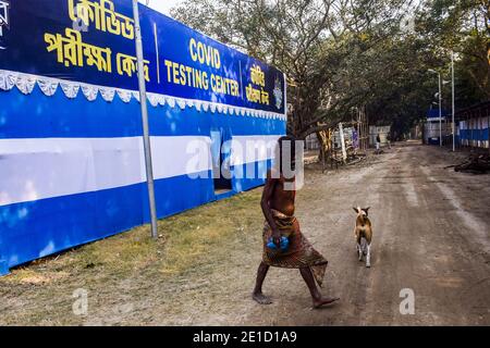 Un pèlerin hindou marchant a passé une bannière de conscience du coronavirus au camp de transit de Gangasagar.le gouvernement du Bengale occidental se prépare à prendre toutes les précautions pour Covid19 car de nombreux pèlerins hindous indiens et Sadhu se rendent à la foire annuelle de Ganga Sagar, Qui se tient sur une île à l'embouchure du fleuve Sacré-Ganges du 9 au 15 janvier. Le camp de transit de Babughat sert d'arrêt pour briser leur voyage à Kolkata. Banque D'Images