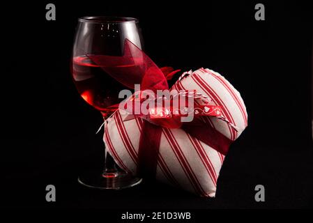 Verre à vin unique avec coeurs de Saint-Valentin sur fond noir. Banque D'Images