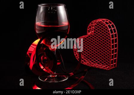 Verre à vin unique avec coeurs de Saint-Valentin sur fond noir. Banque D'Images