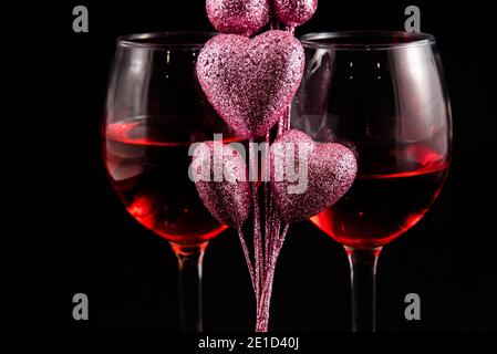 Deux verres à vin avec coeurs de Saint-Valentin sur fond noir. Banque D'Images