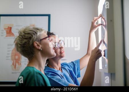 Médecin montrant à sa collègue une radiographie de l'os brisé. Banque D'Images