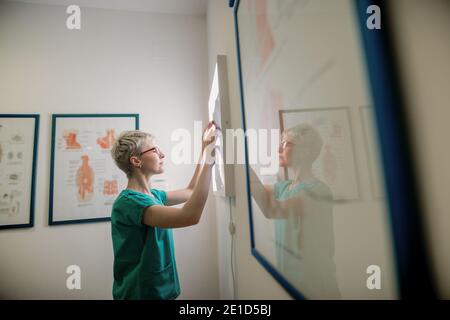 Le médecin examine les rayons X des os cassés du patient. Banque D'Images
