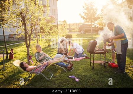 Une grande famille heureuse aime faire un barbecue dans leur jardin lors d'une journée ensoleillée. Banque D'Images