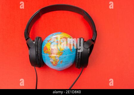 Micro-casque sur globe isolé sur le rouge Banque D'Images