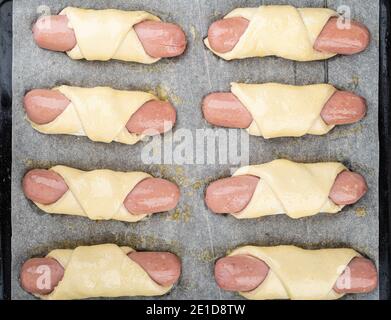 Saucisses dans la pâte sur une plaque de cuisson avant de les placer dans le four. Cuisson au four. Banque D'Images