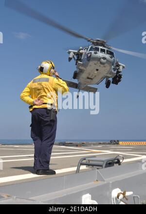 Aviation Boatswain's Mate (Handling) 2nd Class Matthew Kolb salue un hélicoptère MH-60S Sea Hawk affecté à l'hélicoptère Sea combat Squadron (HSC) 22 alors qu'il prend son envol du navire de transport amphibie USS Ponce (LPD 15). Ponce fait partie du Kearsarge Amphiobie Ready Group qui participe à la Force opérationnelle interarmées Odyssey Dawn. Odyssey Dawn est le groupe de travail du Commandement de l'Afrique des États-Unis créé pour assurer le commandement et le contrôle opérationnels et tactiques des forces militaires américaines en soutien à la réponse internationale aux troubles en Libye et à l'application de la résolution du Conseil de sécurité des Nations Unies (UNSCR) Banque D'Images