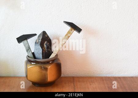 Deux marteaux décoratifs en minerai de morion (quartz noir) et échantillon de minerai de morion dans le pot d'argile sur table en bois Banque D'Images